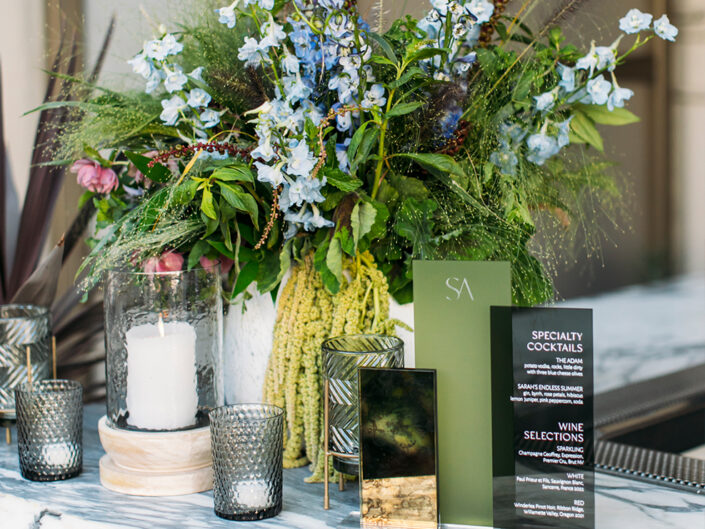 Smokey acrylic signage for a specialty cocktail bar accompanied by silver votive candles