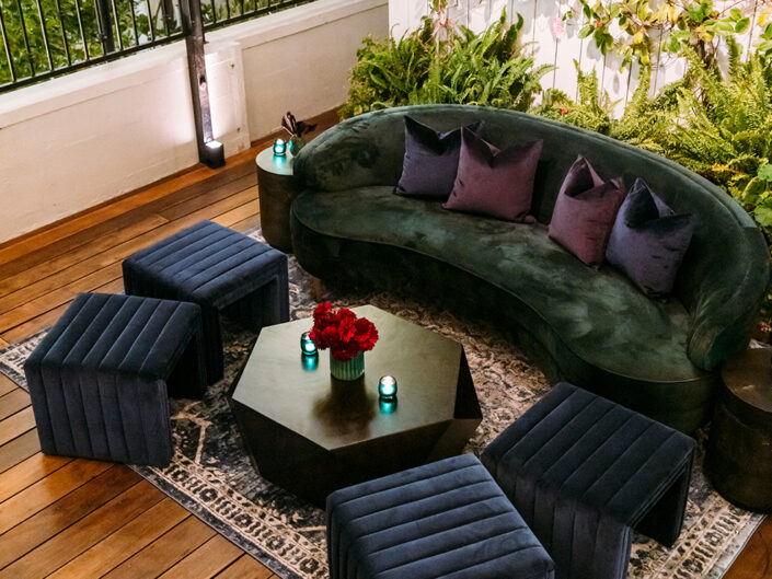 Green velvet lounge accompanied by navy blue upholstered ottomans to create a cozy seating at the after party