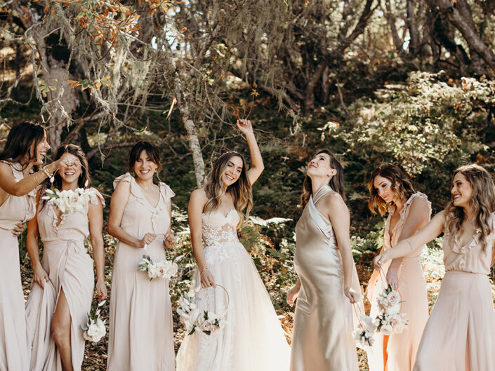 The bride dancing with her bridesmaids, dressed in blush pink and champagne gowns.