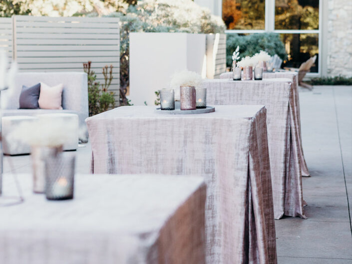 Stand-up tables draped in blush metallic linens, accented with pink and gray votives.