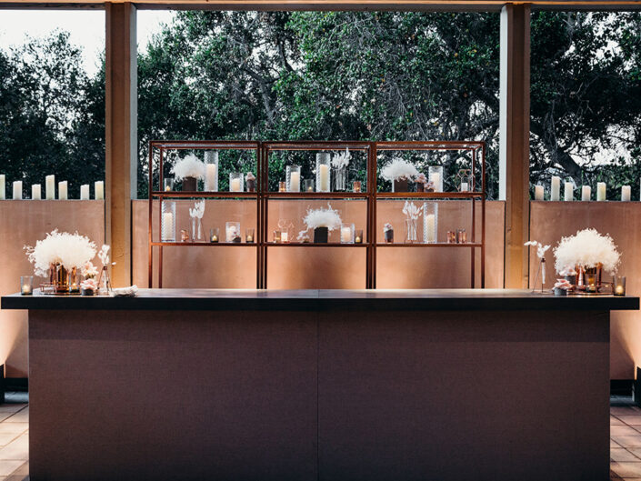 Bars wrapped in grey and gold lurex fabric with pickled wood tops and rose gold glass shelving.