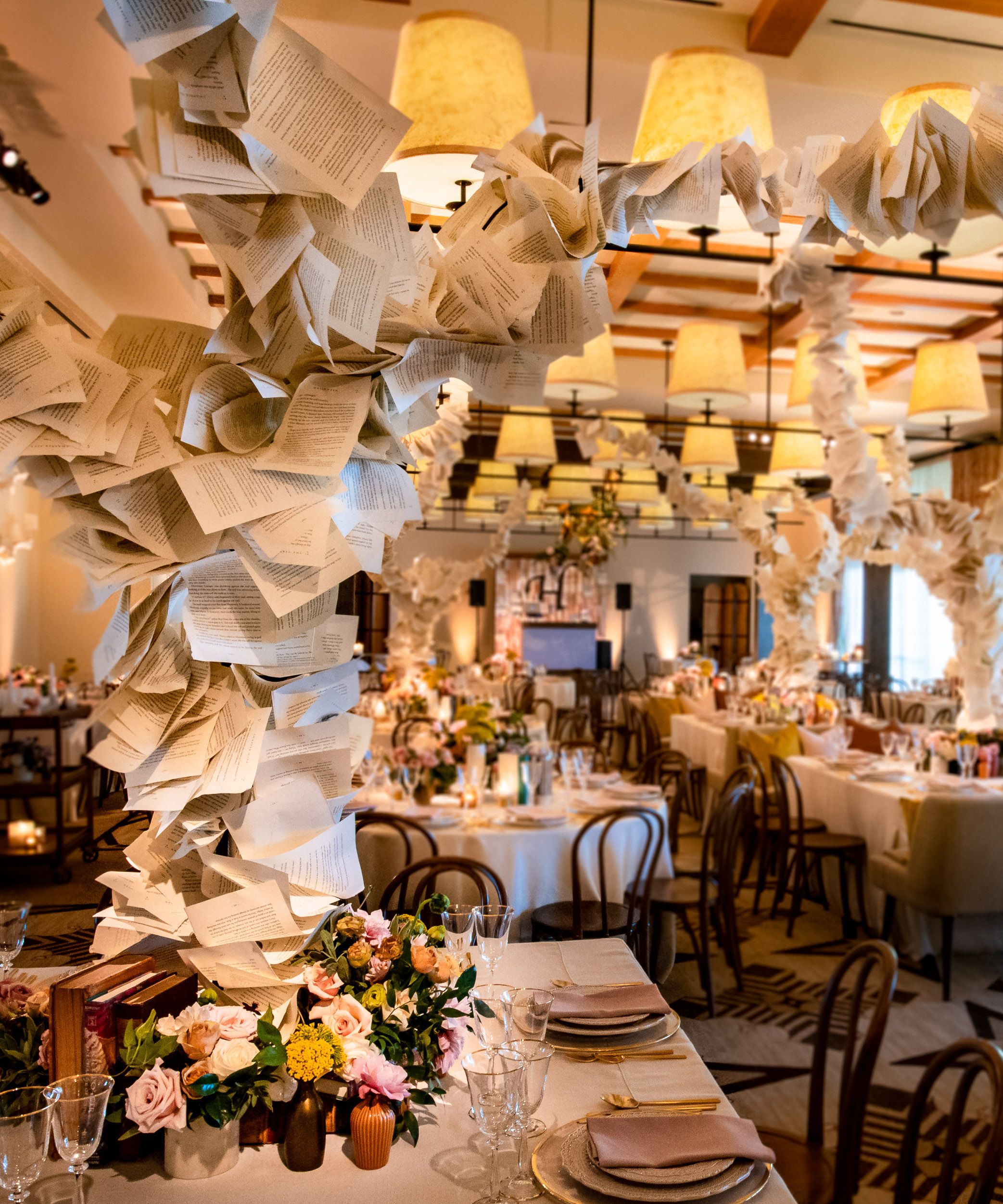 Event dining environment with sculptural book installations rising above carefully styled tables