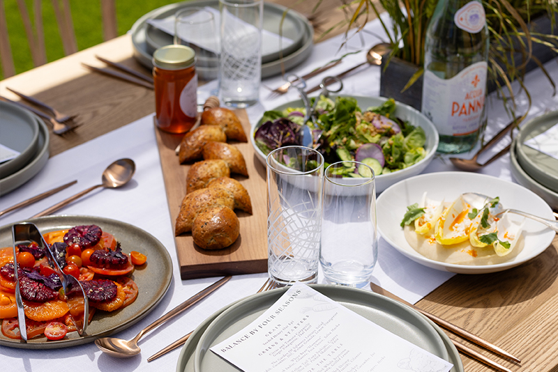 Shared dishes, artisan bread and fresh salads presented on a styled outdoor dining table