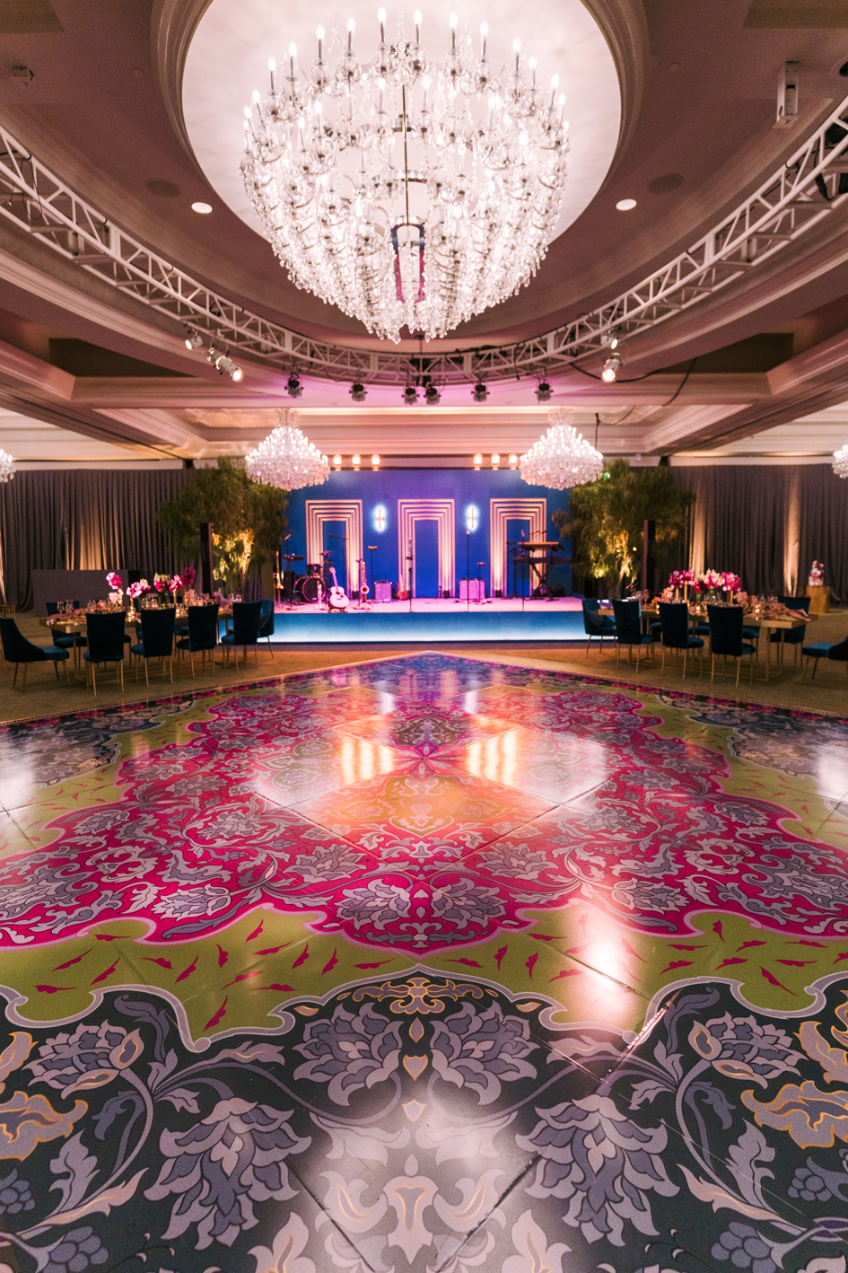 Belgian rug-inspired dance floor facing a peacock blue stage with illuminated gold frames