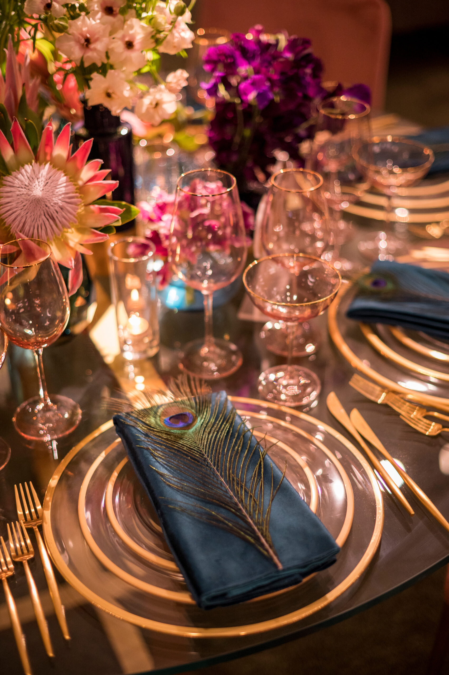Wedding place setting with an indigo velvet napkin, gold-rimmed charger and layered glassware